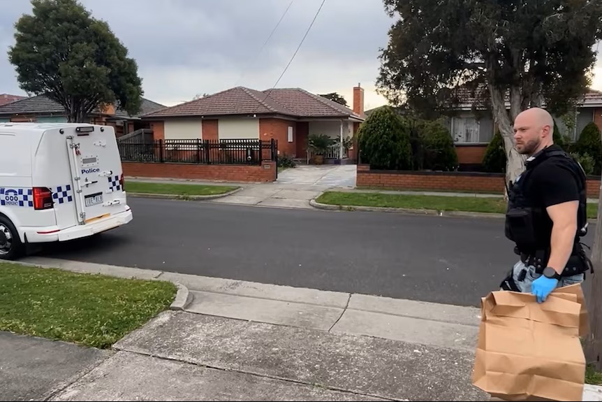 A police officer takes evidence to the police car. SCREENSHOT: Victoria Police/Supplied.
